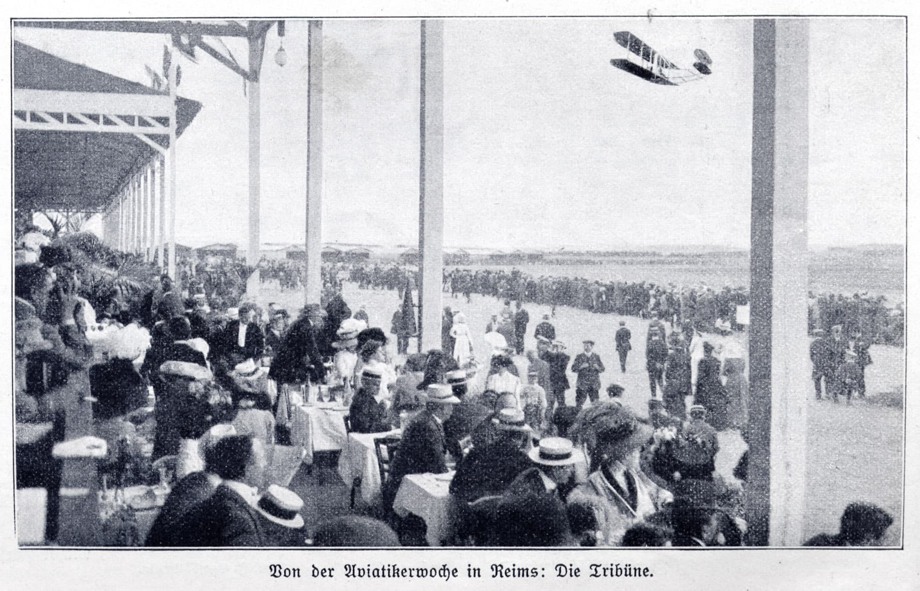 Photograph (taken from a catholic german magazin from 1910) of a biplane flying past the tribune of the Aviation week in Reims, France, August 22 - 29, 1909.