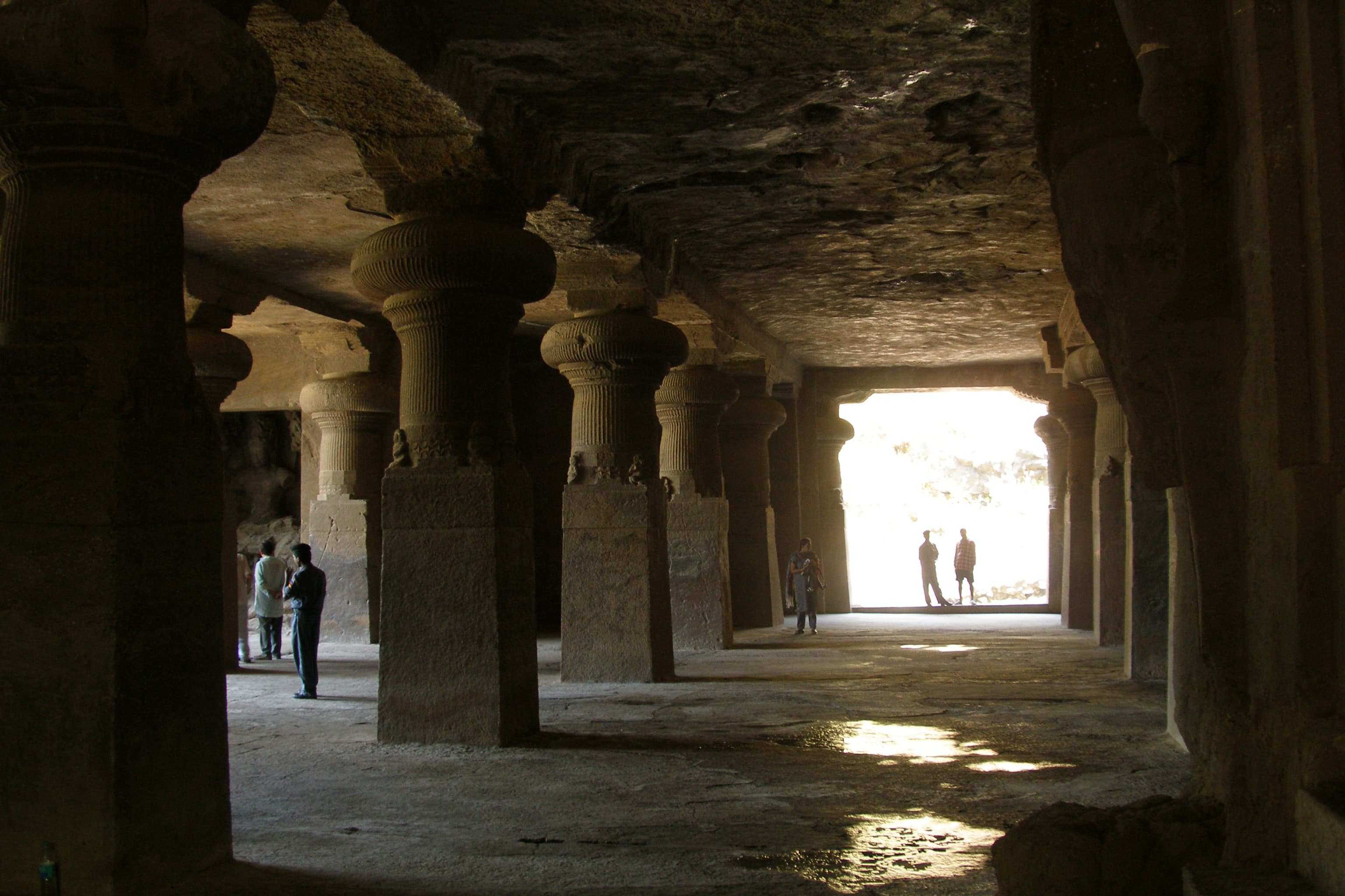 Stone columns and a sunlit doorway inside Elephanta Caves